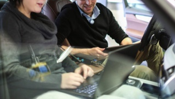 Menschen in Auto mit Laptop