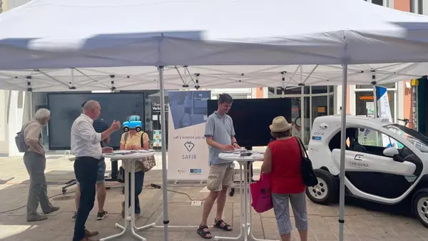 Picture of the research vehicle ANTON (Renault Twizy), and citizens interacting with Prof. Vaculin.