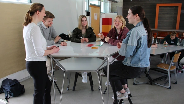 Five people at a desk talking. 