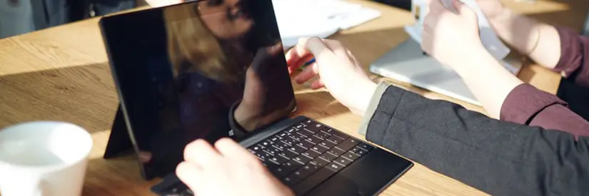 Das Gesicht einer Frau spiegelt sich im Bildschirm ihres Laptops