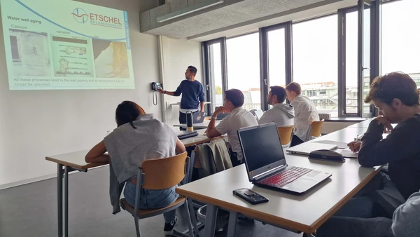 In the lecture hall, a company representative shows a presentation, a group of students looks at it attentively.