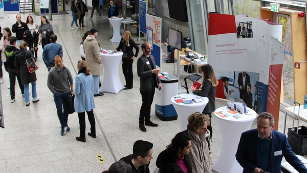 People in a foyer and at the exhibition stand