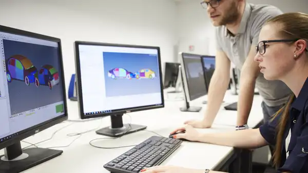 Two employees are sitting in front of a PC.